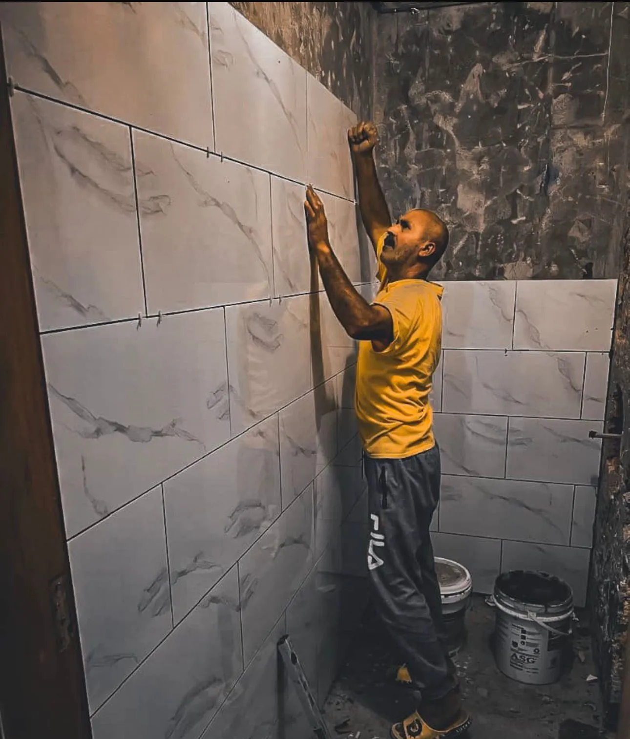 Handyman installing large-format tiles on a bathroom wall