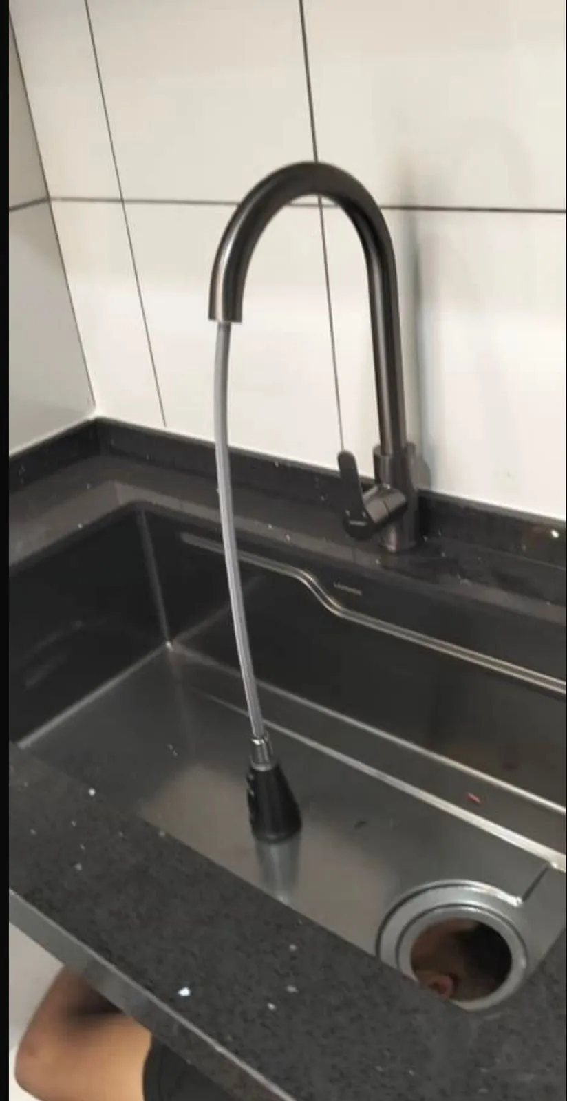 New kitchen faucet installed over a dark countertop sink