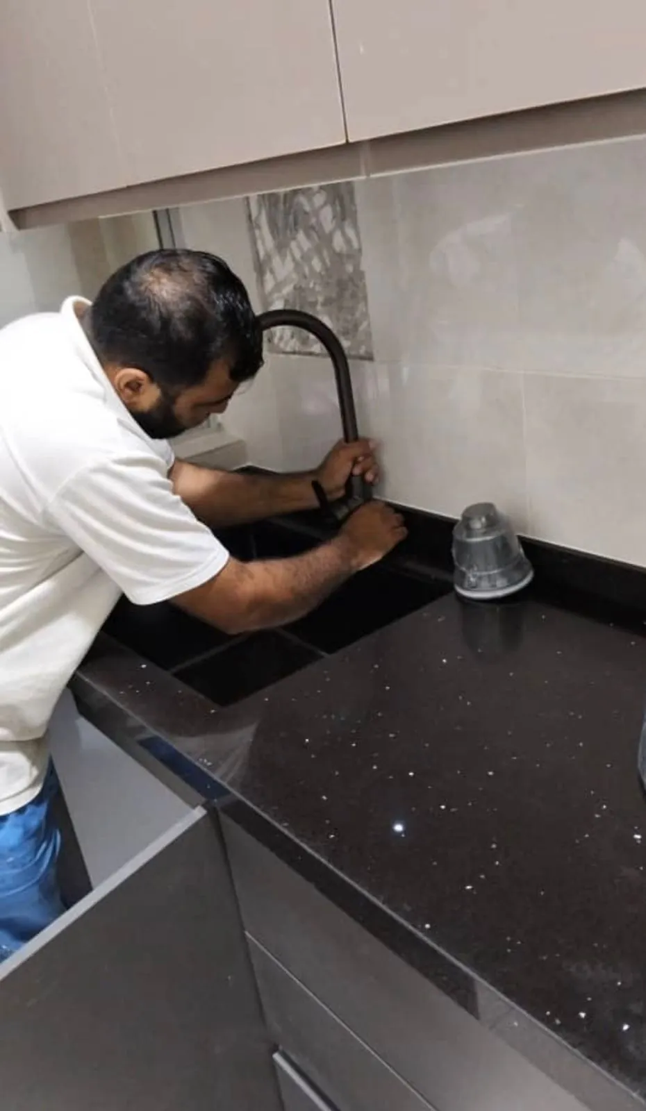 Handyman repairing plumbing beside a kitchen sink