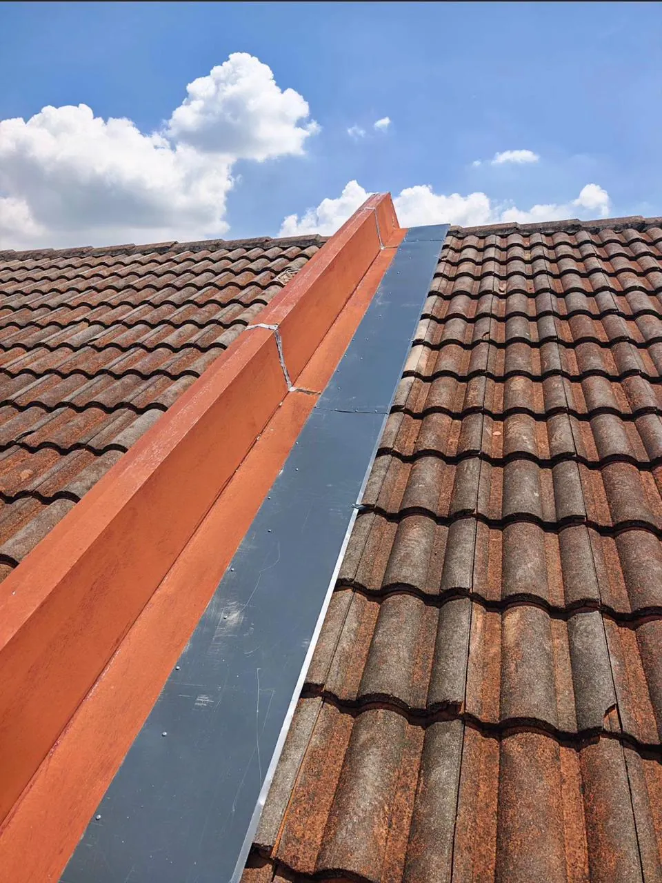 Repaired roof flashing between rows of tiles